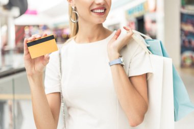 kredi kartı ve alışveriş torbaları tutan gülümseyen genç kadın görüntüsünü kırpılmış