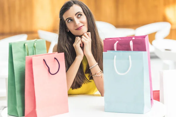 Pensativo Sorrindo Jovem Mulher Sentada Mesa Com Sacos Compras Olhando — Fotos gratuitas