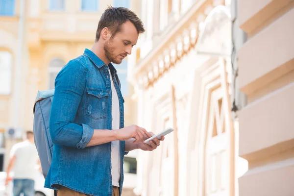 在街上使用智能手机的人在牛仔衬衫侧面视图 — 图库照片