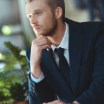 Retrato de hombre de negocios pensativo en traje con taza de café teniendo descanso de café en la cafetería