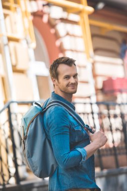 Çekici genç turist tarafından street yürüyüş ve kameraya seyir sırt çantası ile
