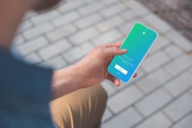 twitter app üstünde perde ile akıllı telefon kullanan adam kırpılmış atış