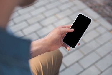 cropped shot of man using smartphone with blank screen on street clipart