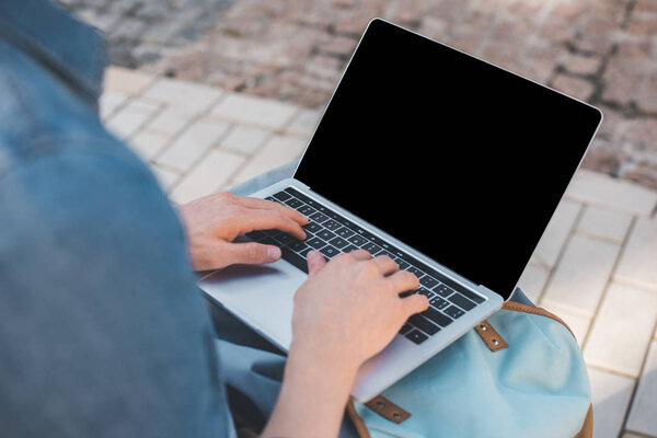 обрезанный снимок человека с помощью ноутбука с пустым экраном на улице
