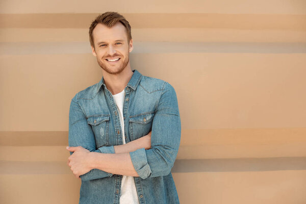 attractive young man looking at camera in front of wall