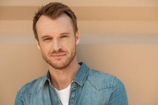 close-up portrait of attractive young man looking at camera in front of wall