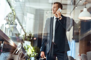 kafede Smartphone cep telefonu ile konuşurken çanta şık iş adamı