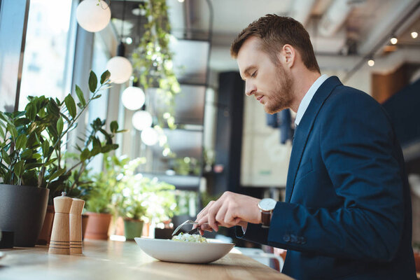 side view of businessman in suit having lunch in cafe