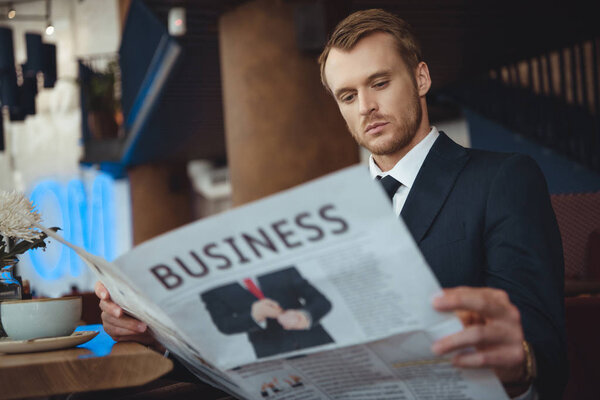 portrait of businessman reading newspaper during coffee break in cafe