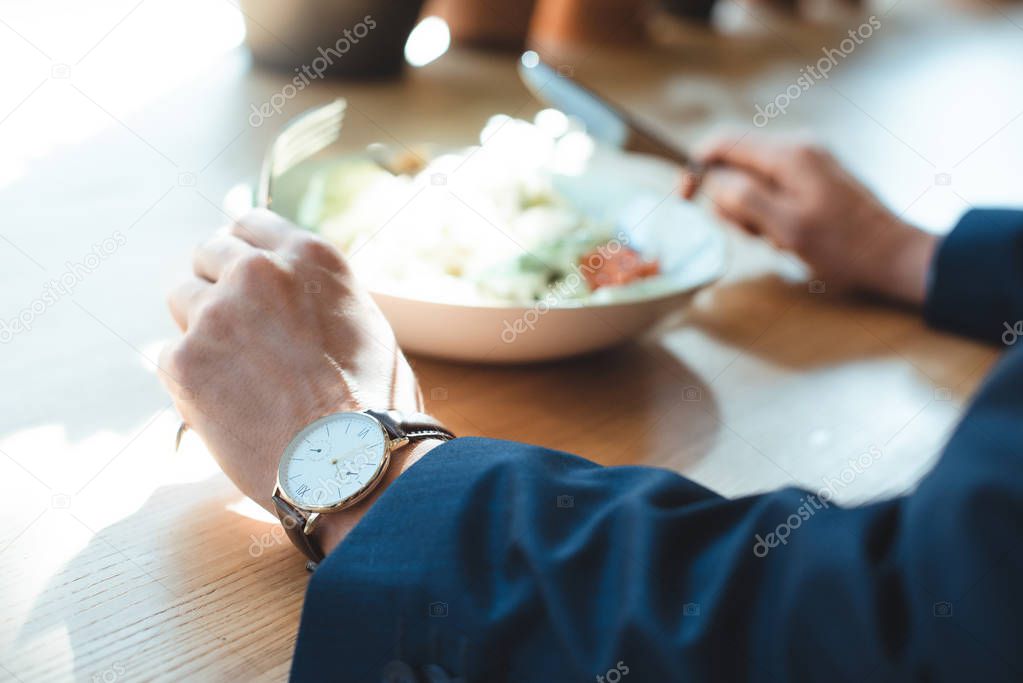 cropped shot of businessman at table with served lunch in restaurant