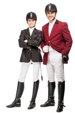 happy young equestrians in uniform and helmets looking at camera isolated on white clipart
