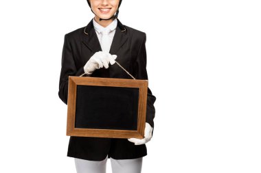 cropped shot of smiling young horsewoman in uniform holding blank chalkboard isolated on white clipart