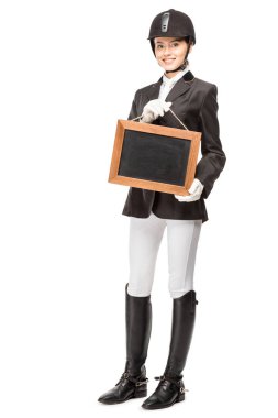 beautiful young horsewoman in uniform holding blank chalkboard isolated on white clipart
