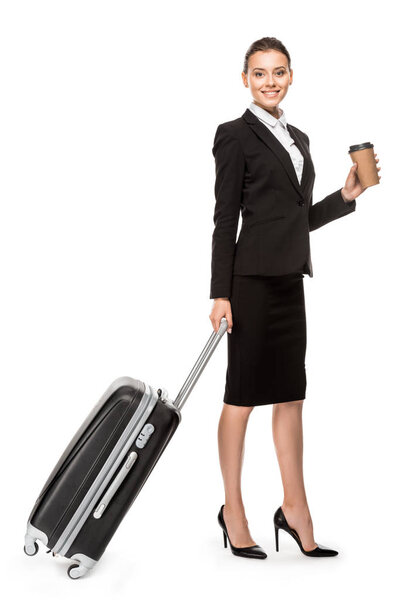 beautiful young businesswoman in suit with luggage and paper cup of coffee looking at camera isolated on white