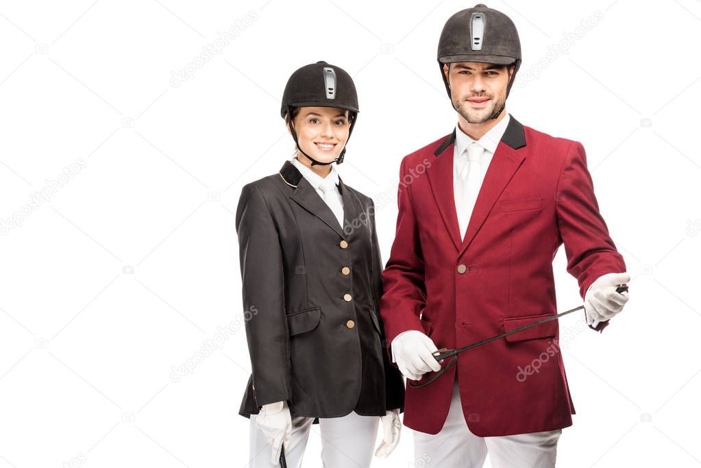 attractive young equestrians in uniform and helmets looking at camera isolated on white
