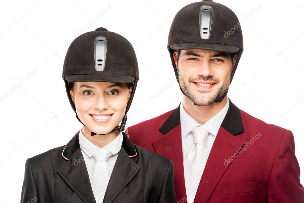 close-up portrait of smiling young equestrians in uniform and helmets looking at camera isolated on white