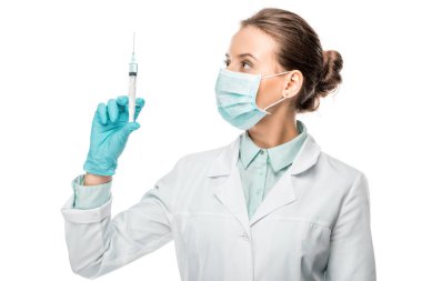 kadın doktor tıbbi maske üzerinde beyaz izole şırınga bakarak 