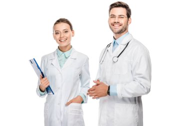 happy female doctor holding clipboard while her male colleague standing near isolated on white  clipart