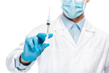 Genç erkek doktor lateks eldiven ve tıbbi maske üzerinde beyaz izole şırınga tutarak kısmi görünümünü 