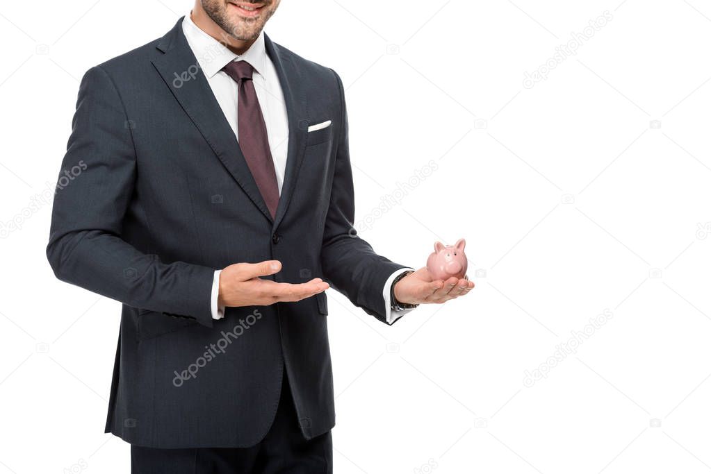 partial view of businessman pointing at pink piggybank isolated on white