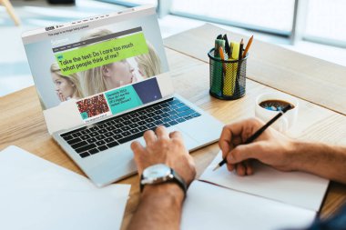 Masa üstü ile defter ve laptop ekranında bbc Web sitesi ile çalışan işadamı kadeh kırpılmış