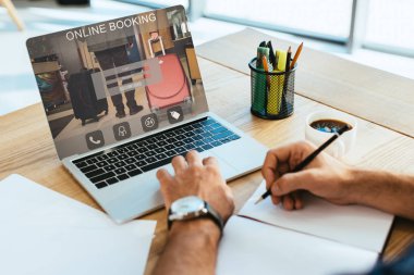 Masa üstü ile defter ve laptop online rezervasyon ekranda yazı ile çalışan işadamı kadeh kırpılmış