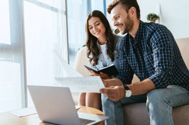 yüzey laptop ve webinar ofiste birlikte katılan kağıtları ile gülümseyen iş arkadaşları