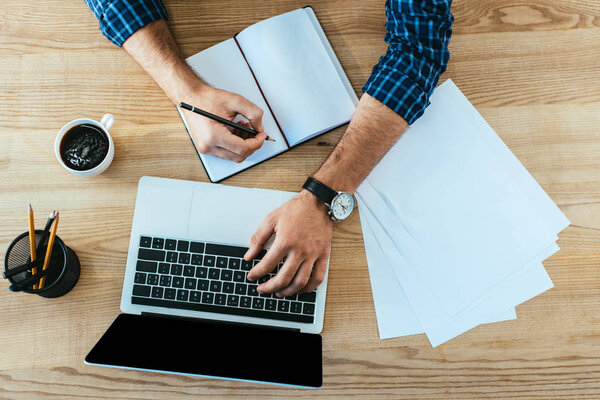 overhead view of man taking part in webinar at tabletop with papers