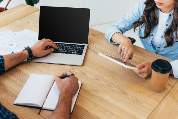 обрезанный снимок бизнес-коллег с ноутбука и планшета, принимающих участие в вебинаре в офисе
