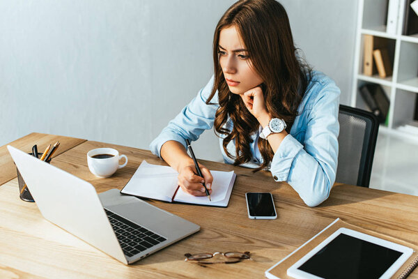 concentrated woman at tabletop with laptop taking part in webinar in office