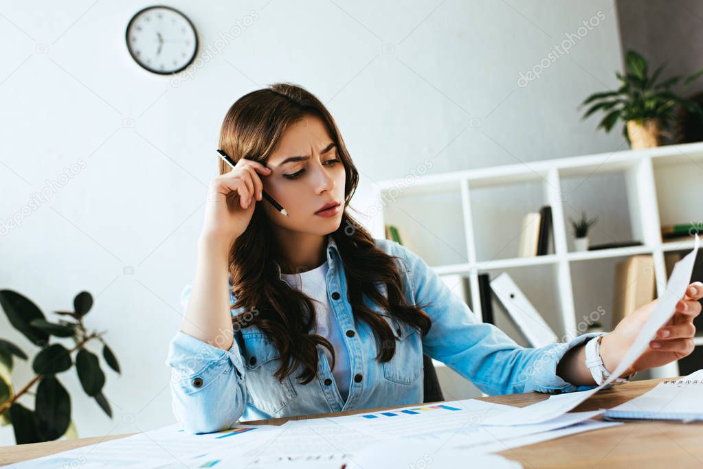 young focused businesswoman doing paperwork at workplace in office