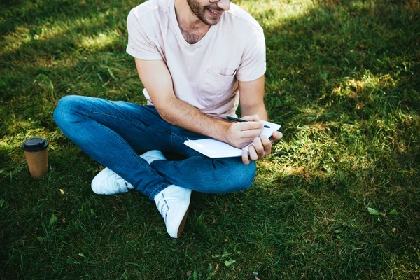 Imagen Recortada Hombre Sonriente Haciendo Notas Sobre Hierba Verde Parque — Foto de Stock