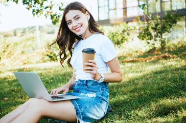 güzel kız katılan webinar Park, kameraya bakarak dizüstü bilgisayar ile gülümseyen