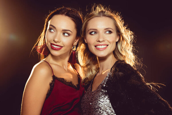 portrait of smiling attractive women in glamour dresses on black with backlit 