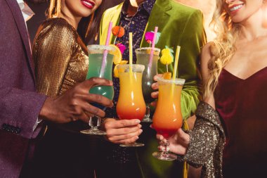cropped view of friends holding alcohol cocktails on party clipart