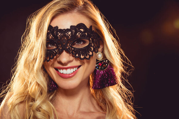 beautiful blonde smiling girl in black carnival mask