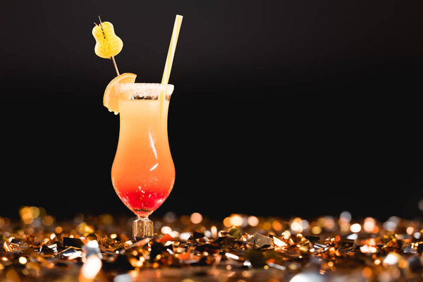 sweet cocktail with straw on golden confetti on black with copy space