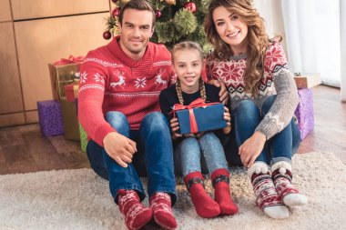 Anne ve kızı ile hediye Noel ağacı yakın oturan ve evde kameraya bakıyor