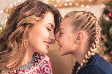 mutlu anne ve kızı evde, burun ile Noel ağacı arka plan üzerinde dokunmadan yan görünüm