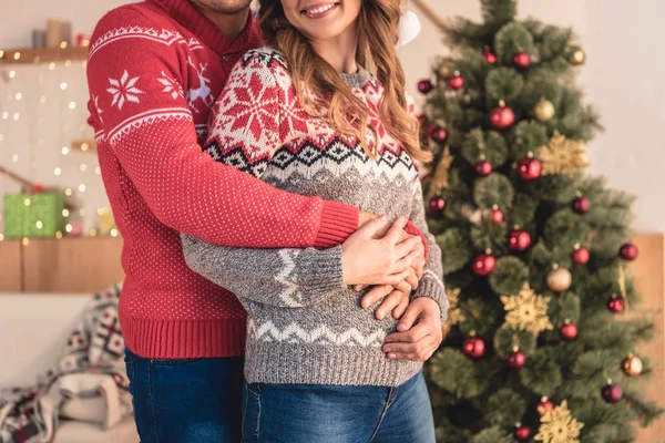 自宅のクリスマス ツリーに近い笑みを浮かべて夫婦ハグのトリミングされた画像 — ストック写真