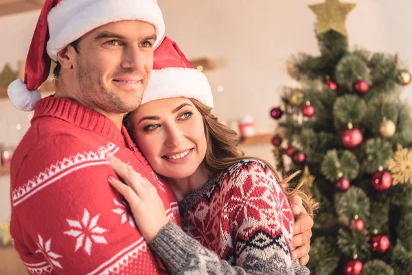 Marito Moglie Cappelli Babbo Natale Coccole Vicino Albero Natale Casa — Foto Stock