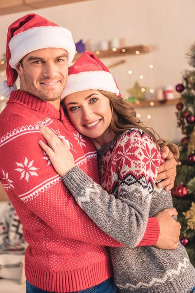 Smiling Husband Wife Santa Hats Hugging Christmas Tree Home Looking — Stock Photo, Image