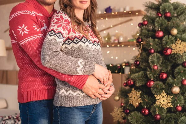Levágott Kép Férje Átölelve Terhes Felesége Otthon Karácsonyfa Közelében — Stock Fotó