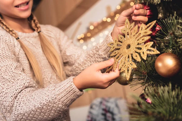 ゴールデン スノーフレーク自宅でクリスマス ツリーを飾るプレティーンの子供の画像をトリミング — ストック写真