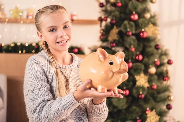 Smiling Preteen Kid Holding Big Piggy Bank Home Christmas Tree — Free Stock Photo