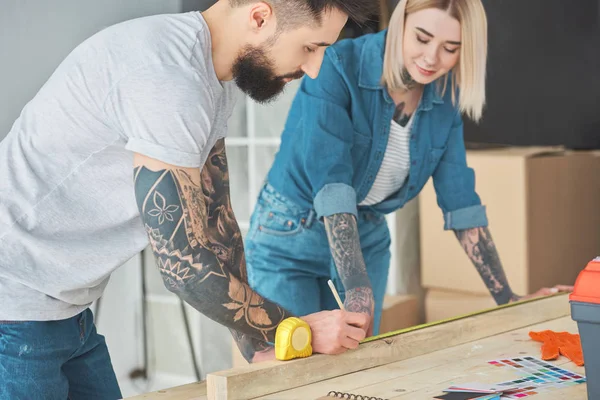 Sonriente Joven Pareja Tatuada Trabajando Con Tablón Madera Cinta Métrica —  Fotos de Stock