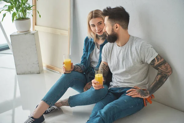 Glada Unga Par Hålla Glas Juice Och Sitter Golvet Nya — Stockfoto