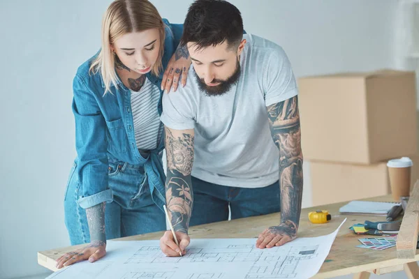 Portrait Tattooed Couple Looking Blueprints Wooden Tabletop New Home — Stock Photo, Image