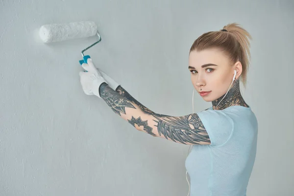 Young Tattooed Woman Earphones Painting Wall New Home — Stock Photo, Image
