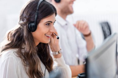 selective focus of smiling female call center operator in office clipart